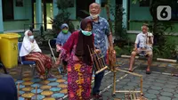 Seorang lansia berjalan saat latihan angklung di Rumah Rehabilitasi Psikososial Dinas Sosial Kota Tangerang, Banten, Rabu (19/5/2021). Kegiatan berlatih angklung bagi lansia tersebut guna mengisi waktu luang sekaligus melatih motorik, auditori, dan sensorik para lansia. (Liputan6.com/Angga Yuniar)