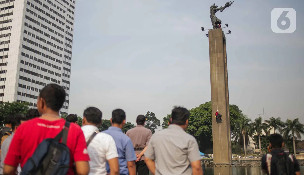 Aktivis lingkungan Green Peace turun usai membentangkan spanduk di Patung Selamat Datang, Bunderan HI, Jakarta, Rabu (23/10/2019). Dalam aksi yang telah berlangsung selama 13 jam tersebut, mereka diamankan oleh petugas kepolisian yang telah berjaga dibawah. (Liputan6.com/Faizal Fanani)