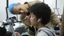 Model saat dirias di belakang panggung sebelum memamerkan koleksi busana wanita Fall Winter 2020 Jil Sander selama Fashion Week di Milan, Italia, Rabu, (19/2/2020). (AP Photo/Domenico Stinellis)