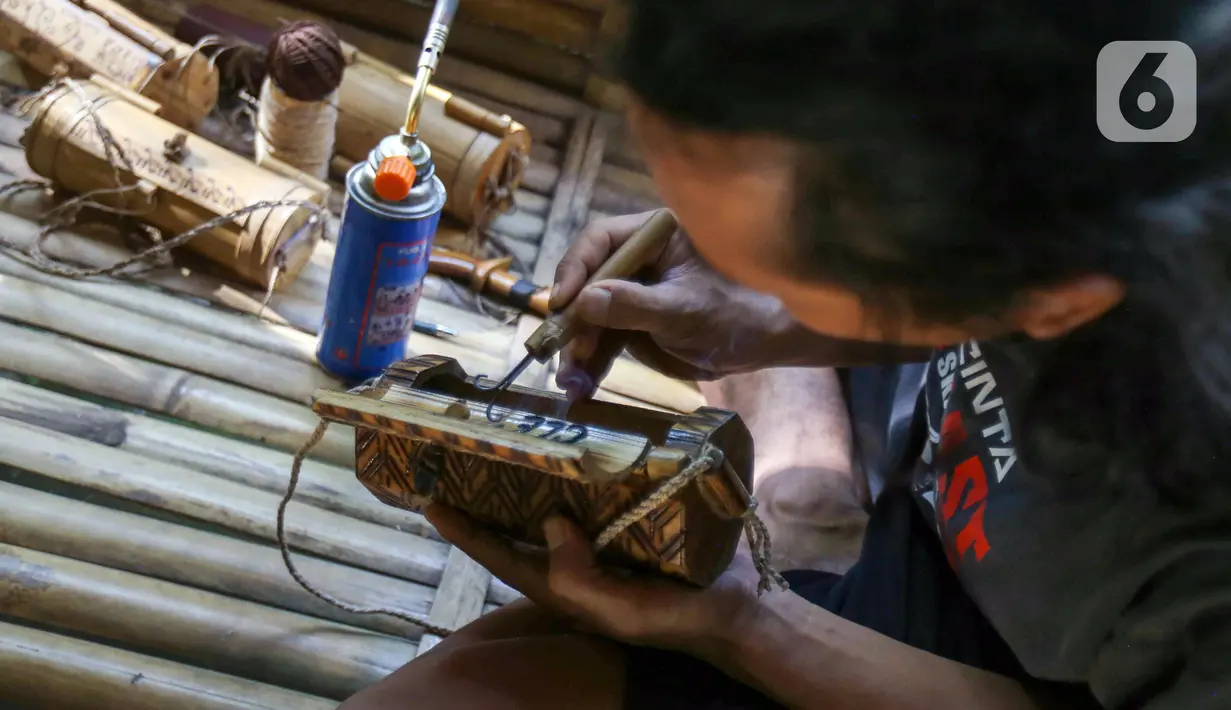 Perajin membuat kerajinan tas dari limbah bambu di Grand Depok City, Depok, Jawa Barat, Kamis (2/6/2022). Komunitas Ciliwung Depok (KCD) memanfaatkan limbah bambu yang berada di Sungai Ciliwung menjadi kerajinan seperti tas, tempat alat tulis, dan cangkir. (Liputan6.com/Herman Zakharia)