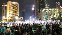 Warga menikmati car free night saat malam pergantian tahun di kawasan Bundaran HI, Jakarta, Senin (31/12). Hujan yang mengguyur Jakarta sejak siang tidak menyurutkan antusias warga menikmati car free night. (Liputan6.com/Angga Yuniar)