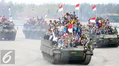 Warga membawa bendera merah putih saat menaiki tank TNI menyaksikan HUT TNI ke-70 di Dermaga Indah Kiat, Cilegon, Banten, Senin (5/10/2015). HUT TNI Ke-70 ditandai atraksi tempur tiga matra TNI Angkata Darat, Laut dan Udara. (Liputan6.com/Faisal Fanani)