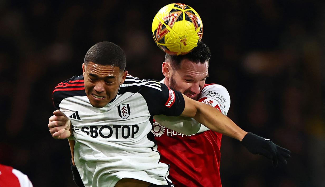 Pemain Fulham, Carlos Vinicius (kiri) berebut bola dengan pemain Rotherham, Sean Morrison pada laga putaran ketiga Piala FA 2023/2024 yang berlangsung di Craven Cottage, London, Inggris, Sabtu (06/01/2023). (AFP/Henry Nicholls)