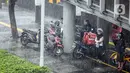 Warga berteduh saat turun hujan di Jalan Jenderal Sudirman, Jakarta, Minggu (18/10/2020). Badan Meteorologi, Klimatologi, dan Geofisika (BMKG) menyatakan musim hujan berlangsung mulai Oktober dan diprediksi mencapai puncaknya pada Januari hingga Februari 2021. (Liputan6.com/Faizal Fanani)