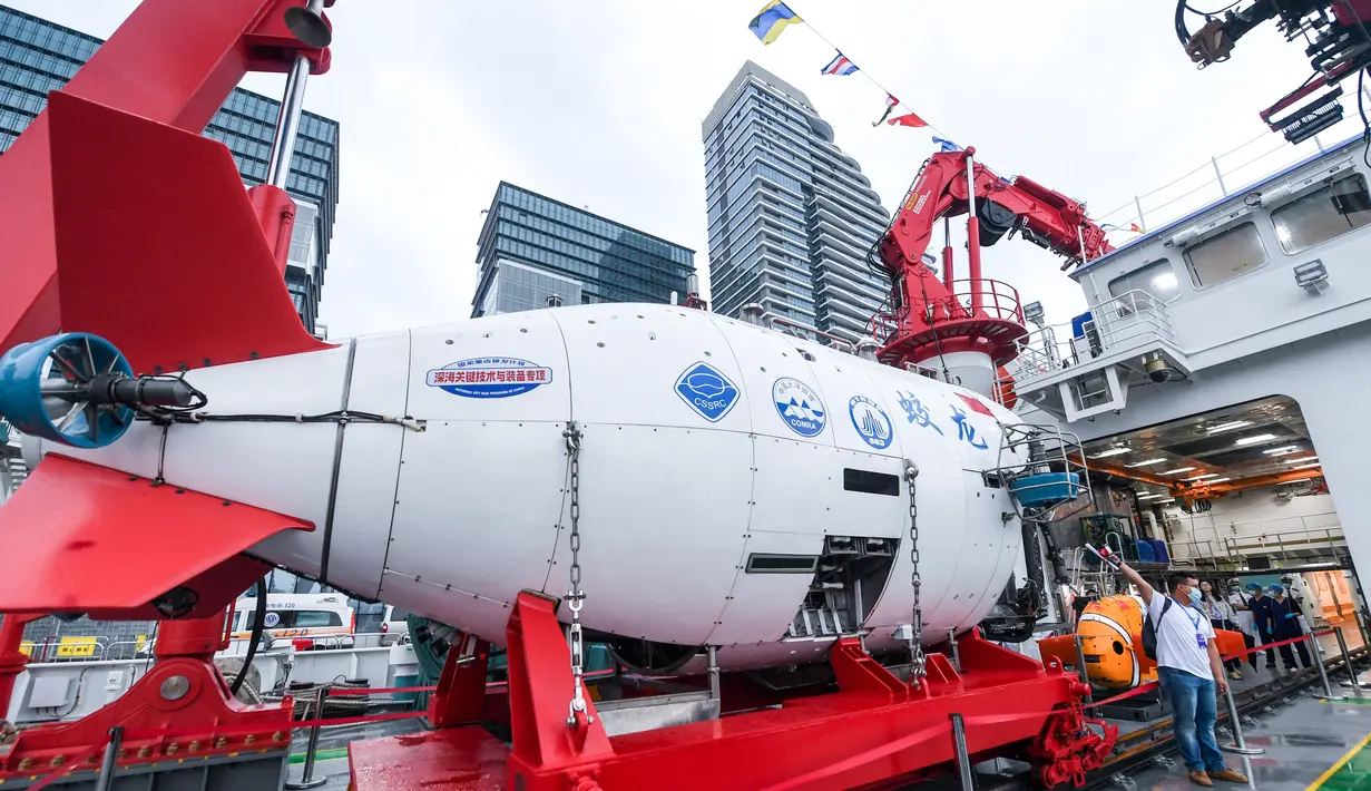 Seorang jurnalis bekerja di sebelah kapal selam berawak Jiaolong di atas kapal induknya, Shenhai Yihao (Laut Dalam No. 1), di sebuah pelabuhan di Shenzhen, Provinsi Guangdong, China selatan (13/10/2020). (Xinhua/Mao Siqian)