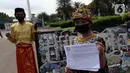 Demonstran melakukan aksi teatrikal saat unjuk rasa di kawasan Bundaran Patung Kuda Arjuna Wijaya, Jakarta, Senin (21/6/2021). Aksi yang dilakukan bertepatan dengan ulang tahun Presiden Joko Widodo ini sebagai bentuk kecaman dan penolakan terhadap revisi UU Minerba. (Liputan6.com/Angga Yuniar)