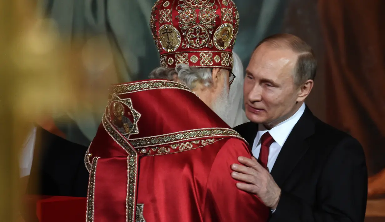  Presiden Rusia, Vladimir Putin memeluk kepala Gereja Ortodoks Rusia usai menjalani prosesi Paskah Ortodoks di Gereja Katedral Kristus Juru Selamat di Moskow, Rusia, (16/4). (AFP Photo / Vasily Maximov)
