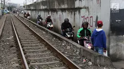 Sejumlah pengendara melintas di samping rel kereta yang berada di kawasan Banjir Kanal Barat, Jakarta, Selasa (20/3). Aksi nekat tersebut membahayakan diri sendiri maupun pengguna jalan lain. (Liputan6.com/Arya Manggala)