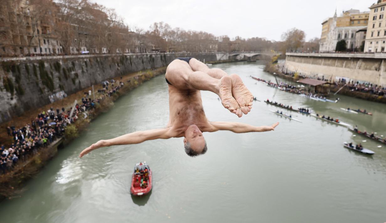 Marco Fois menyelam ke dalam Sungai Tiber untuk merayakan tahun baru 2024 di Roma, Italia, Senin (1/1/2024). (AP Photo/Domenico Stinellis)