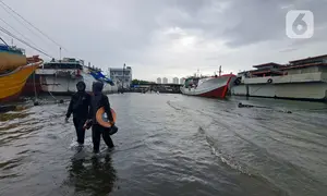 Nelayan melintasi banjir rob saat cuaca ekstrem di Pelabuhan Muara Baru, Penjaringan, Jakarta Utara, Rabu (28/12/2022). Banjir ROB, hujan deras dan  cuaca buruk melanda kawasan Pelabuhan Muara Baru saat siang menjelang sore hari. (Liputan6.com/Johan Tallo)