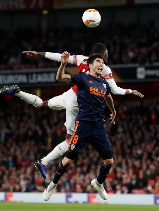Duel udara pemain Valencia, Carlos Soler dengan gelandang Arsenal, Ainsley Maitland-Niles dalam leg pertama semifinal Liga Europa di Emirates Stadium, Jumat (3/5/2019). Sempat tertinggal, Arsenal berhasil mengalahkan tamunya, Valencia dengan skor 3-1. (Reuters/Paul Childs)
