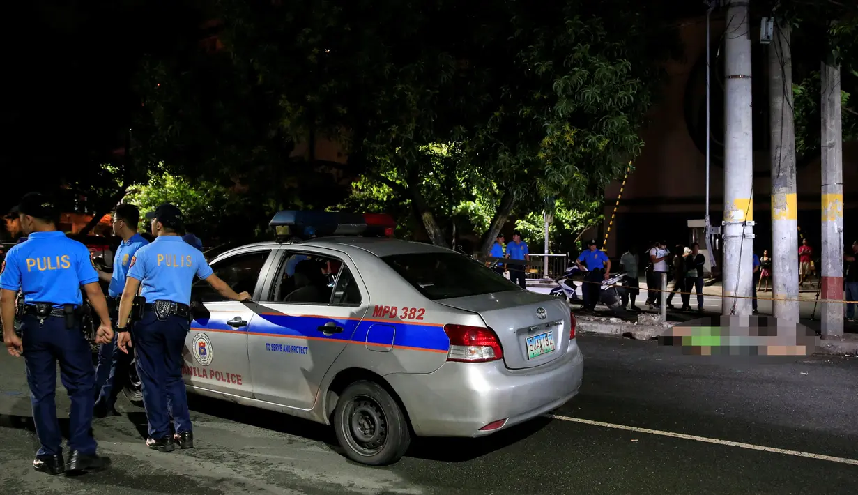 Petugas berjaga di samping jenazah pria yang diduga bandar narkoba di pinggir jalan Malate, Manila (29/8). Kondisi jenazah ini sama seperti tragedi sebelumnya, yakni luka tembak dan pistol di tangan. (REUTERS/Romeo Ranoco)