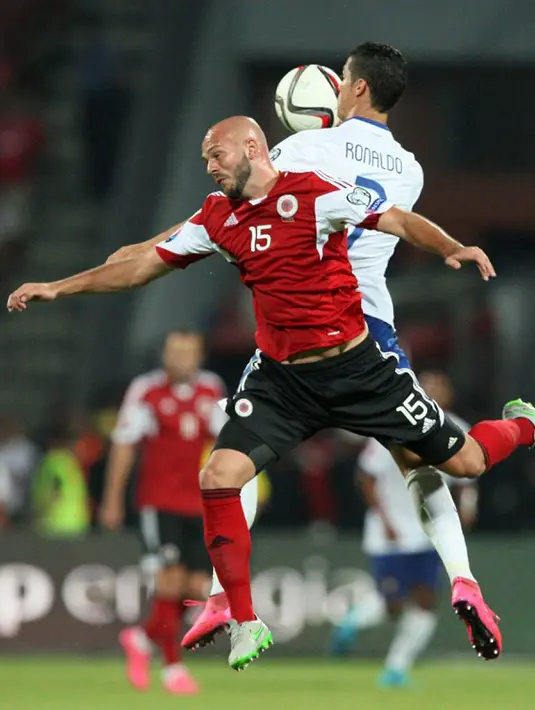 Pertarungan udara antara Cristiano Ronaldo dengan pemain Albania, Arlind Ajeti dalam kualifikasi Euro 2016 di Elbasan Arena, Selasa (8/9/2015). Portugal menang 1-0 atas gol Miguel Veloso di saat injury time. (AFP Photo/Gent Shkullaku)