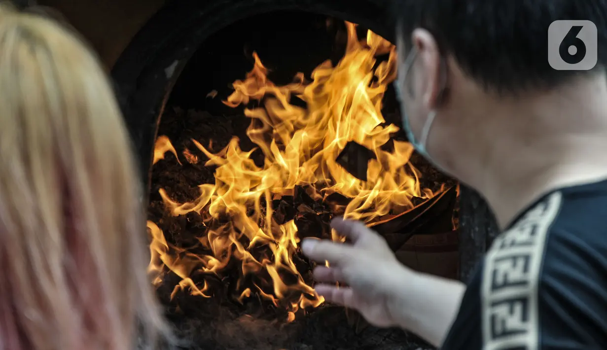 Warga keturunan Tionghoa membakar kertas saat sembahyang Tahun Baru Imlek 2573 Kongzili di Vihara Amurva Bhumi, Jakarta, Selasa (1/2/2022). Pengurus membatasi 50 persen pengunjung dari kapasitas normal dalam kegiatan sembahyang Imlek guna mencegah penularan Covid-19. (merdeka.com/Iqbal S Nugroho)