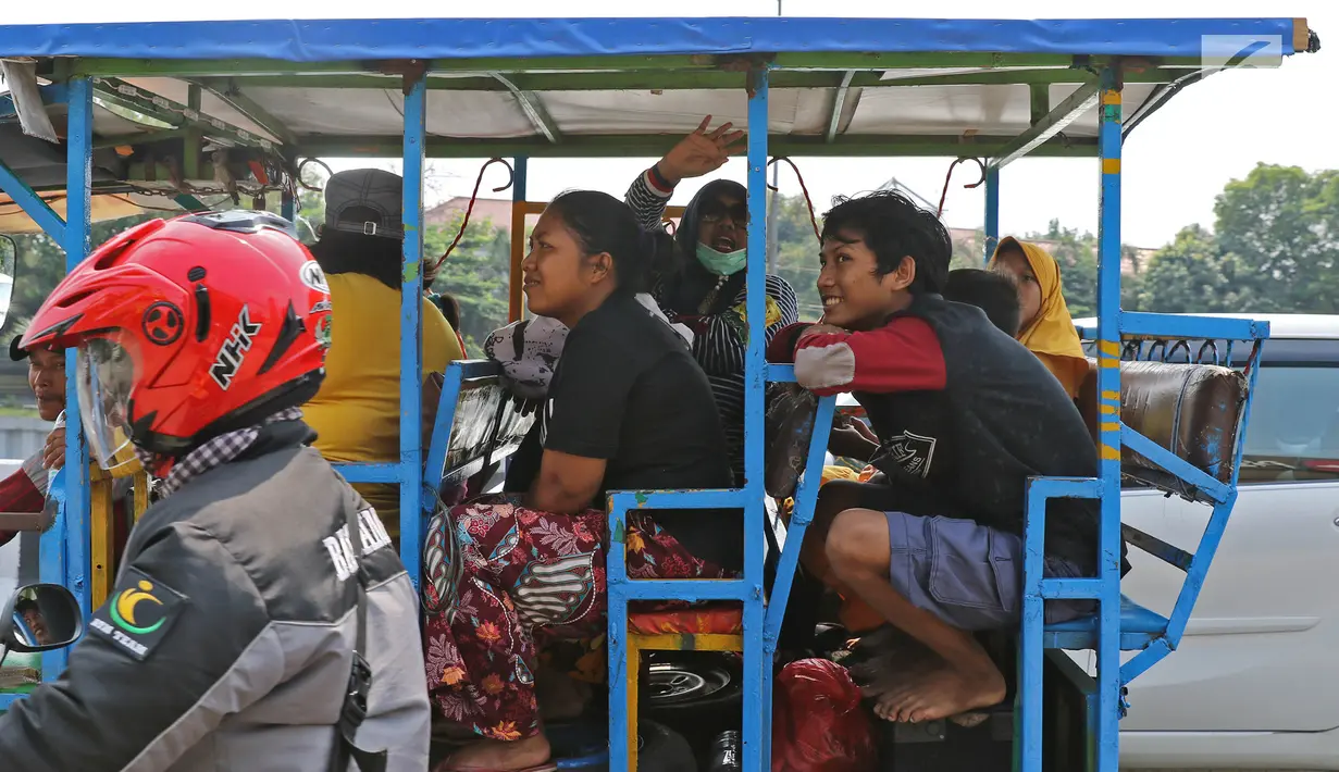 Sejumlah warga menaiki bak terbuka motor roda tiga menuju Kebun Binatang Ragunan di kawasan Jakarta, Minggu (9/6/2019). Warga memanfaatkan motor roda tiga untuk bepergian bersama keluarga menuju sejumlah objek wisata karena dianggap lebih hemat biaya. (Liputan6.com/Herman Zakharia)