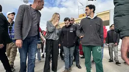 Dalam kunjungannya, Angelina Jolie sempat berbincang langsung dengan anggota Bulan Sabit Merah Mesir dan para sukarelawan serta pengemudi truk yang membawa bantuan kemanusiaan ke perbatasan. Tampak dalam foto, aktris Amerika Serikat (AS), Angelina Jolie (kedua kiri) saat tiba di perbatasan Rafah Mesir, pada Jumat 2 Januari 2026. (Foto oleh AFP)