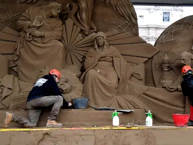 Seniman Rusia Ilya Filimontsev (kiri) dan seniman Ceko Radovan Zivny (kanan) saat membuat patung pasir adegan kelahiran Yesus di St Peter, Vatikan, Kamis (6/12). Patung ini dipersiapkan untuk menyambut Natal. (Tiziana FABI/AFP)