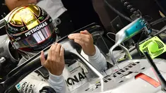 Pembalap Mercedes, Lewis Hamilton memasuki mobilnya saat sesi latihan pertama jelang GP F1 Abu Dhabi di Sirkuit Yas Marina, Jumat (23/11). Hamilton tampil berbeda dengan nomor balap yang melekat pada mobilnya. (GIUSEPPE CACACE/AFP)