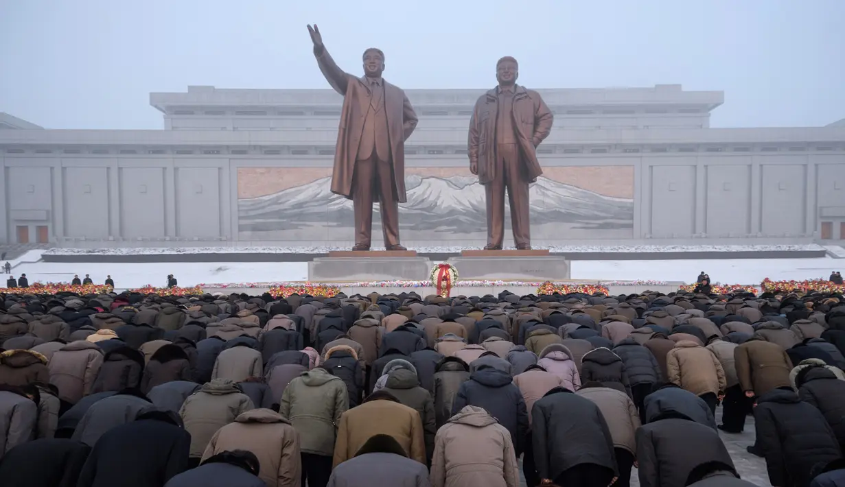 Penduduk Pyongyang memberi hormat di hadapan patung pemimpin Korea Utara Kim Il Sung dan Kim Jong Il selama Hari Peringatan Nasional di Bukit Mansu, Pyongyang (17/12).  Korea Utara tengah memperingati 7 tahun wafatnya  Kim Jong Il. (AFP Photo/Kim Won Jin)