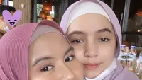 Sienna tampil mengenakan kerudung model pashmina model plisket warna ungu yang serasi dengan Nesyana. Sienna pun mengenakan ciput putih dan busana warna ungu. Credit: (@nesyanabila)