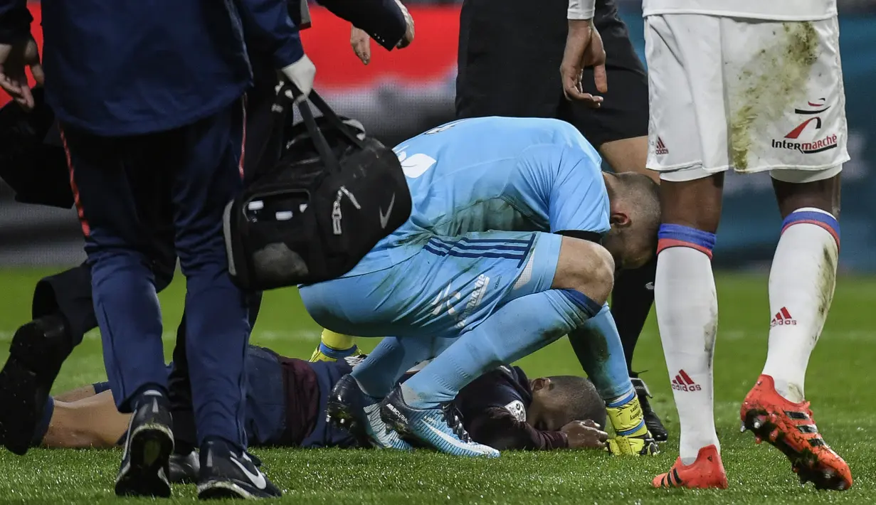 Pemain Paris Saint-Germain, Kylian Mbappe tersungkur di lapangan saat lanjutan Ligue 1 di Groupama Stadium, Senin (22/1). Mbappe mengalami cedera setelah berbenturan dengan kiper Olympique Lyon, Anthony Lopes. (AFP PHOTO / JEFF PACHOUD)