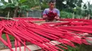 Seorang pekerja menjemur hio dupa di sentra industri kecil pembuatan hio di Tangerang, Banten, Senin (9/1/2023). Jelang perayaan Imlek, pesanan hio dupa mengalami peningkatan untuk kebutuhan sembahyang. (Liputan6.com/Angga Yuniar)