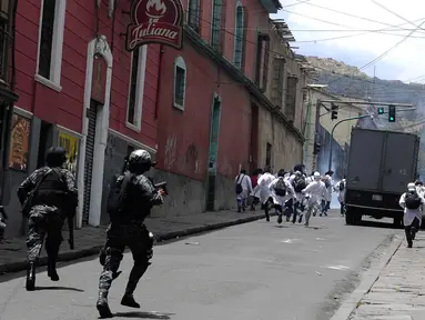 Mahasiswa kedokteran melarikan diri dari polisi anti huru hara saat bentrokan memprotes melawan undang-undang baru Presiden Evo Morales yang menghukum hukuman karena malapraktik medis di dekat lapangan Murilo di La Paz (19/12). (AFP Photo/Jorge Bernal)