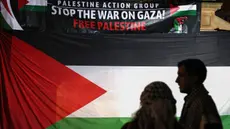 Para pengunjuk rasa pro-Palestina berdiri di depan bendera dan spanduk besar dalam unjuk rasa yang diadakan untuk menandai peringatan "Nakba" atau "Malapetaka" tahun 1948, di Sydney pada tanggal 15 Mei 2024. (DAVID GRAY/AFP)