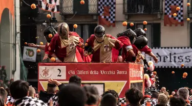 Peserta dan pasukan penjaga saling melemparkan jeruk sebagai bagian dari tradisi "perang jeruk" selama Karnaval Ivrea di Turin, Italia, Minggu (3/3). Festival ini biasa dilaksanakan di bulan Februari setiap tahunnya selama tiga hari (MARCO BERTORELLO/AFP)