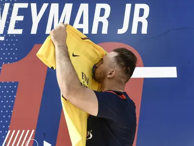 Fans mencium jersey pemain baru Paris Saint Germain, Neymar Jr, di toko merchandise di Paris, Jumat (4/8/2017). Setelah resmi bergabung dengan Paris Saint Germain, jersey Neymar Jr langsung diburu suporter klub Ibu kota. (AFP/Philippe Lopez)