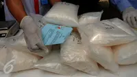 Petugas BNN menunjukkan barang bukti narkotika jenis sabu yang disita dari dua kelompok pengedar di Gedung BNN Jakarta, Kamis (29/10/2015). Sabu seberat 22,4 kg dimusnahkan BNN dihadapan sejumlah saksi dan tersangka. (Liputan6.com/Helmi Fithriansyah)