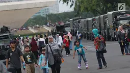 Warga bersama anak-anak berjalan-jalan di kawasan Monumen Nasional, Jakarta, Jumat (19/4). Libur panjang perayaan Paskah 2019 dimanfaatkan warga untuk berwisata di kawasan Monumen Nasional. (Liputan6.com/Helmi Fithriansyah)