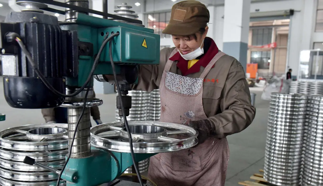 Seorang pekerja wanita membuat lubang baut pada pelek di pabrik pembuatan pelek sepeda motor di Jinhua, Provinsi Zhejiang, China (14/1). (AFP Photo/China Out)