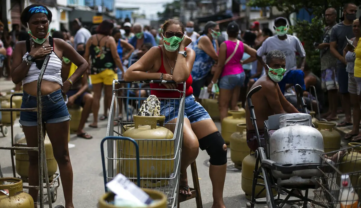 Warga memakai masker saat antre membeli gas murah dari Petrobrás Oil Tankers Union di favela Vila Vintem, Rio de Janeiro, Brasil, Jumat (12/3/2021). Kegiatan ini sebagai kampanye solidaritas untuk memperingati Hari Perjuangan Nasional Pertahanan Perusahaan Milik Negara. (AP Photo/Bruna Prado)