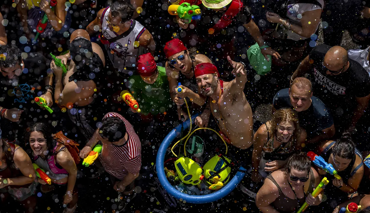 Orang-orang mengikuti perang air tahunan di jalan-jalan lingkungan Vallecas, Madrid, Spanyol, 17 Juli 2022. Kegembiraan terlihat pada wajah para peserta. (AP Photo/Manu Fernandez)