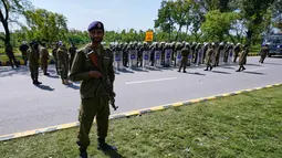 Sejumlah personel militer dan polisi Pakistan bersenjata lengkap menjaga seluruh ruas jalan, terutama yang menuju lokasi perundingan. Tampak dalam foto, seorang petugas polisi berjaga sementara yang lain mengikuti pengarahan sebelum penugasan mereka untuk memastikan keamanan menjelang kemungkinan negosiasi antara Amerika Serikat dan Iran di ibu kota Pakistan, Islamabad, Jumat 10 April 2026. (AP Photo/Anjum Naveed)