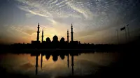 Matahari terbenam di belakang Masjid Agung Sheikh Zayed di Abu Dhabi, Uni Emirat Arab (8/11/2019). Masjid ini adalah masjid terbesar ketiga di dunia setelah masjid di Mekkah dan Madinnah. (AFP Photo/Kamran Jebreili)