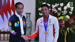 Presiden Joko Widodo atau Jokowi (kiri) bersalaman dengan sprinter Lalu Muhammad Zohri (kanan) di Istana Bogor, Jawa Barat, Rabu (18/7). Zohri tampak mengenakan medali emas yang diraihnya di Finlandia. (Liputan6.com/Pool/Biro Pers Setpres)