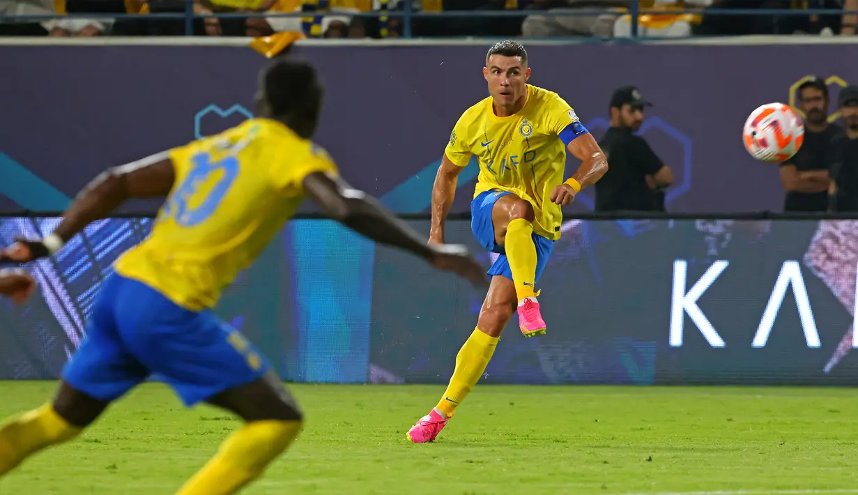 Pemain Al Nassr, Cristiano Ronaldo (kanan), menendang bola ke gawang Al Taawon dalam laga pekan ke-2 Liga Arab Saudi 2023/2024 yang berlangsung di KSU Football Stadium, Sabtu (19/8/2023) dini hari WIB. Al Nassr mencatatkan percobaan tembakan dibabak pertama, tapi hanya dua yang tepat sasaran. (AFP/Fayez Nureldine)