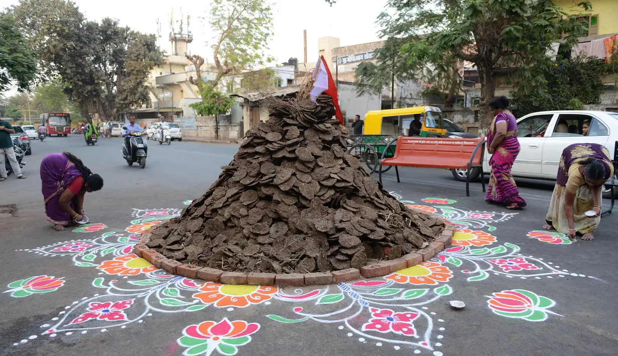 Warga menghiasi jalan di sekitar "Holika", Ahmedabad, India, Minggu (12/3). Bahan bakar Holika adalah kue yang terbuat dari kotoran sapi dan kelapa. (AFP PHOTO / SAM PANTHAKY)