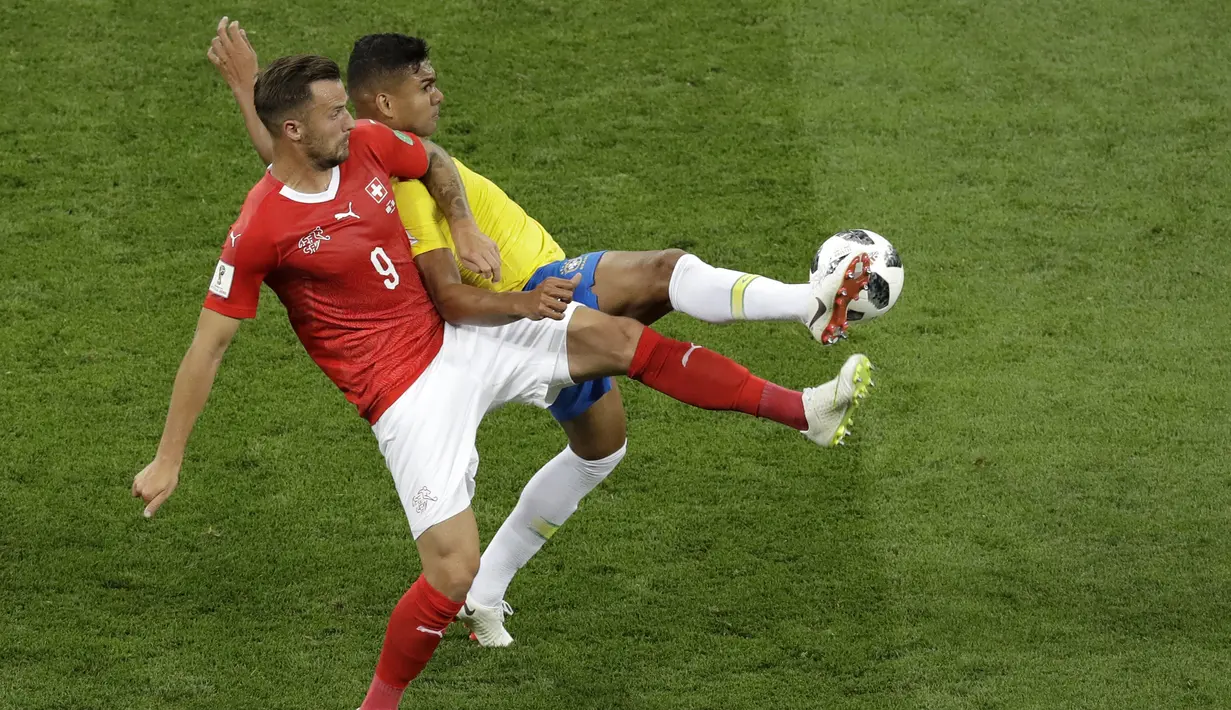 Striker Swiss, Haris Seferovic, berebut bola dengan gelandang Brasil, Casemiro, pada laga Grup E Piala Dunia di Rostov Arena, Rostov-on-Don, Minggu (17/6/2018). Kedua negara bermain imbang 1-1. (AP/Andrew Medichini)