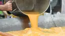 Anggota World Giant Omelette Brotherhood menuangkan telur ke atas wajan untuk membuat omelet raksasa di Malmedy, Belgia, Selasa (15/8). Dengan ukuran sebesar itu, dibutuhkan waktu memasaknya jauh lebih lama, yaitu 30 hingga 40 menit. (JOHN THYS/AFP)