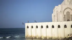 Seorang pria melompat untuk menyelam ke Samudra Atlantik dari dinding masjid Hassan II di Casablanca, Maroko (7/2/2020). Masjid ini memiliki minaret yang paling tinggi di dunia dengan ketinggian 210 meter (689 kaki) dan memiliki kapasitas 25.000 orang. (AP Photo/Mosaab Elshamy)