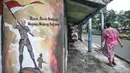 Warga melintas di depan mural bertemakan Pancasila di Kampung Pancasila kawasan Galur, Johar Baru, Jakarta, Selasa (1/6/2021). Kelurahan Galur membuat Kampung Pancasila yang dihiasi mural sebagai bentuk mengingatkan masyarakat akan Pancasila sebagai dasar negara. (merdeka.com/Iqbal S. Nugroho)
