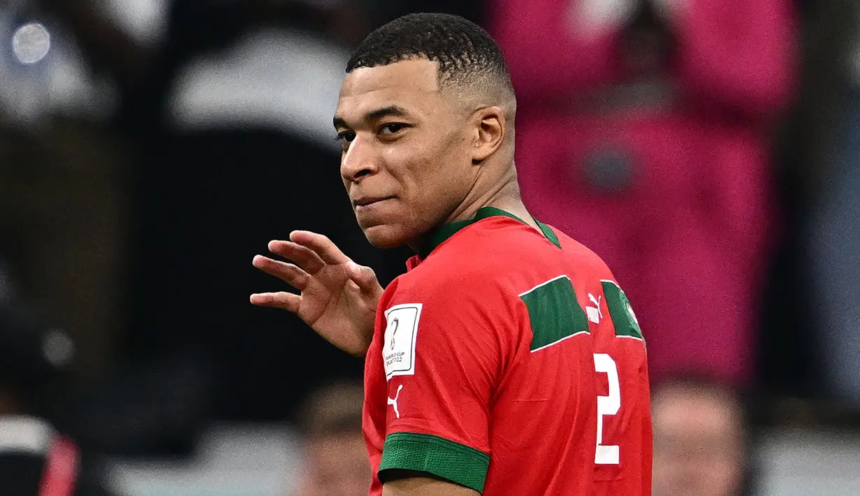Pemain Prancis, Kylian Mbappe mengenakan baju milik pemain Maroko, Achraf Hakimi berjalan meninggalkan lapangan setelah laga semifinal Piala Dunia 2022 yang berlangsung di Al Bayt Stadium, Qatar, Rabu (14/12/2022) waktu setempat. Prancis menang dengan skor 2-0 melalui gol Theo Hernandez dan Randal Kolo Muani. (AFP/Gabriel Bouys)