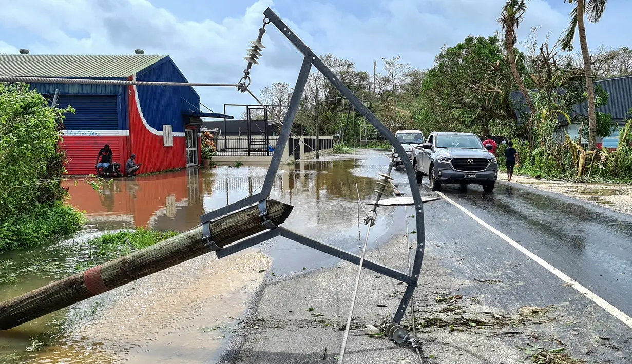 Gambar selebaran ini diambil dan dirilis pada 4 Maret 2023 menunjukkan pengendara yang bepergian melewati kabel listrik yang tumbang di Port Vila. Vanuatu telah meminta bantuan dari tetangga, Australia -tiga jam perjalanan dengan pesawat. Dan Canberra merespons dengan mengatakan akan mengirim air dan pasokan medis serta tim untuk menaksir kerusakan. (Jean-Baptiste Jeangène Vilmer / FRENCH EMBASSY VANUATU / AFP)