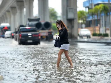 Seorang wanita menyeberangi sebuah jalan yang terendam banjir pascahujan lebat di Bangkok, Thailand (31/8/2020). (Xinhua/Rachen Sageamsak)