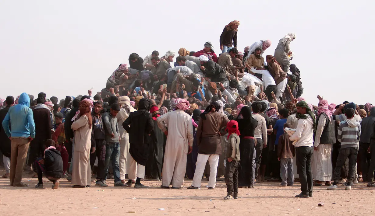 Pengungsi Irak membeli makanan dan minuman usai melarikan diri dari Mosul yang dikuasai oleh ISIS di perbatasan Irak, Hasaka Governorate (23/10). Kota Mosul saat ini tengah terjadi pertempuran antara koalisi Irak melawan ISIS. (REUTERS/Rodi Said)