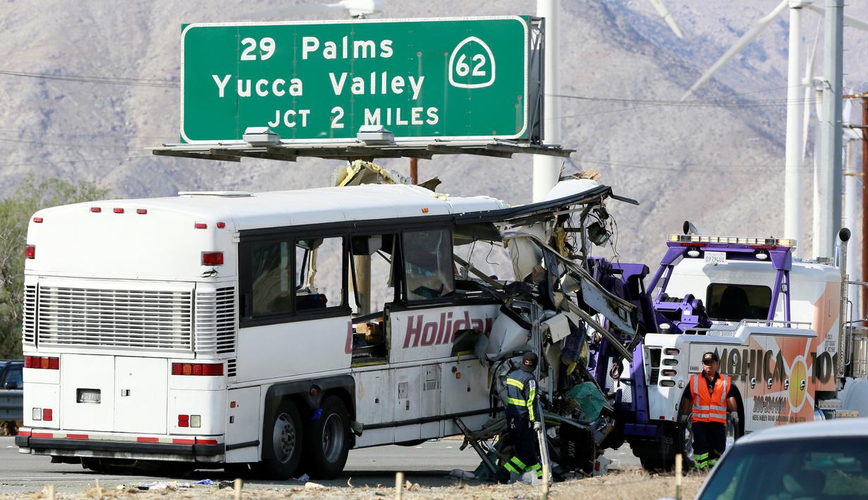Petugas menderek sebuah bus pariwisata yang ringsek akibat bertabrakan dengan truk di Jalan Raya Southern California, Amerika Serikat, (23/10).  Kecelakaan tersebut terjadi pada pagi hari, dimana seluruh penumpang tengah tertidur. (REUTERS/Sam Mircovich)
