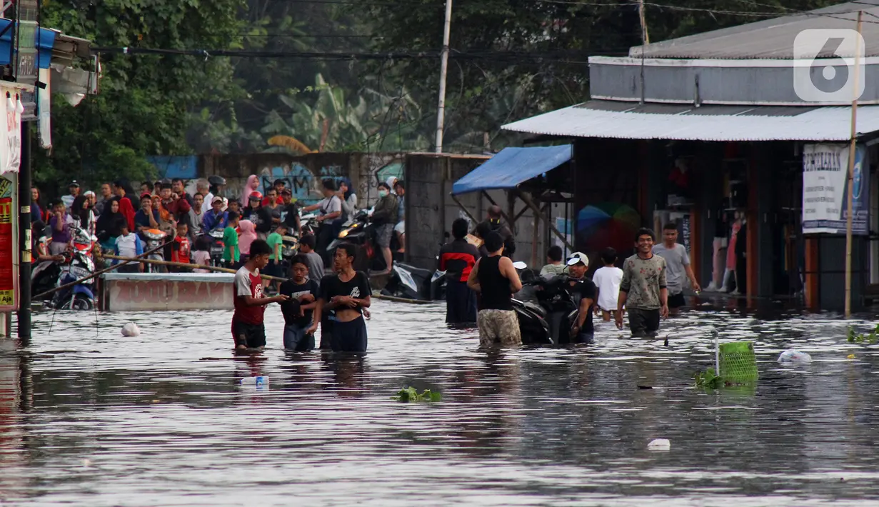 Warga melintasi banjir yang merendam perumahan Villa Mutiara Pluit, Tangerang, Banten, Senin (3/2/2020). Banjir disebabkan jebolnya tanggul sungai di sekitar kawasan tersebut. (merdeka.com/Magang/Muhammad Fayyadh)